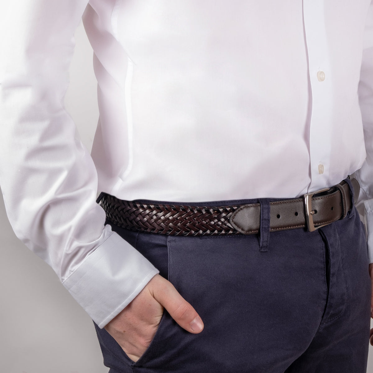 Men's woven leather belt with satin nickel buckle in brown, side close up, hand in pocket