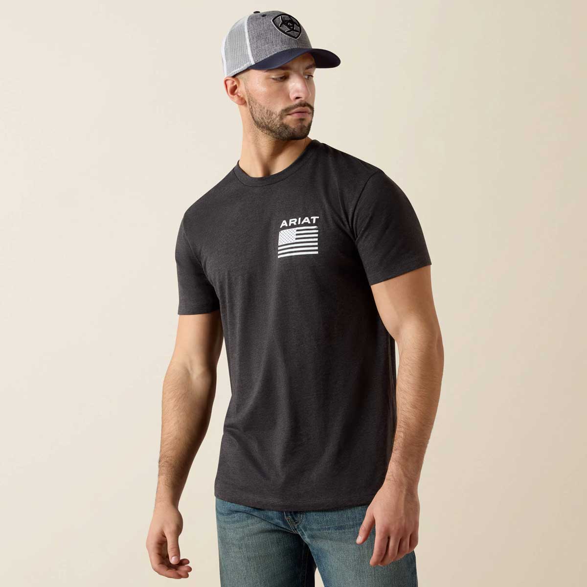 Man wearing a black t-shirt with Ariat logo and gray cap on beige background