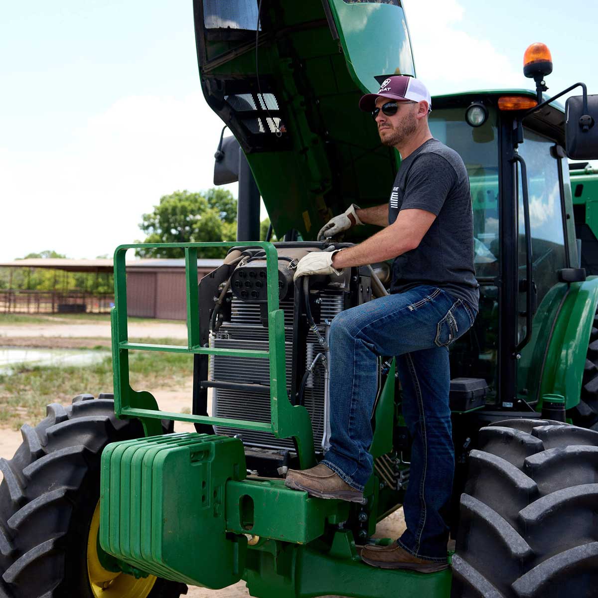Man working on a green tractor in an outdoor setting