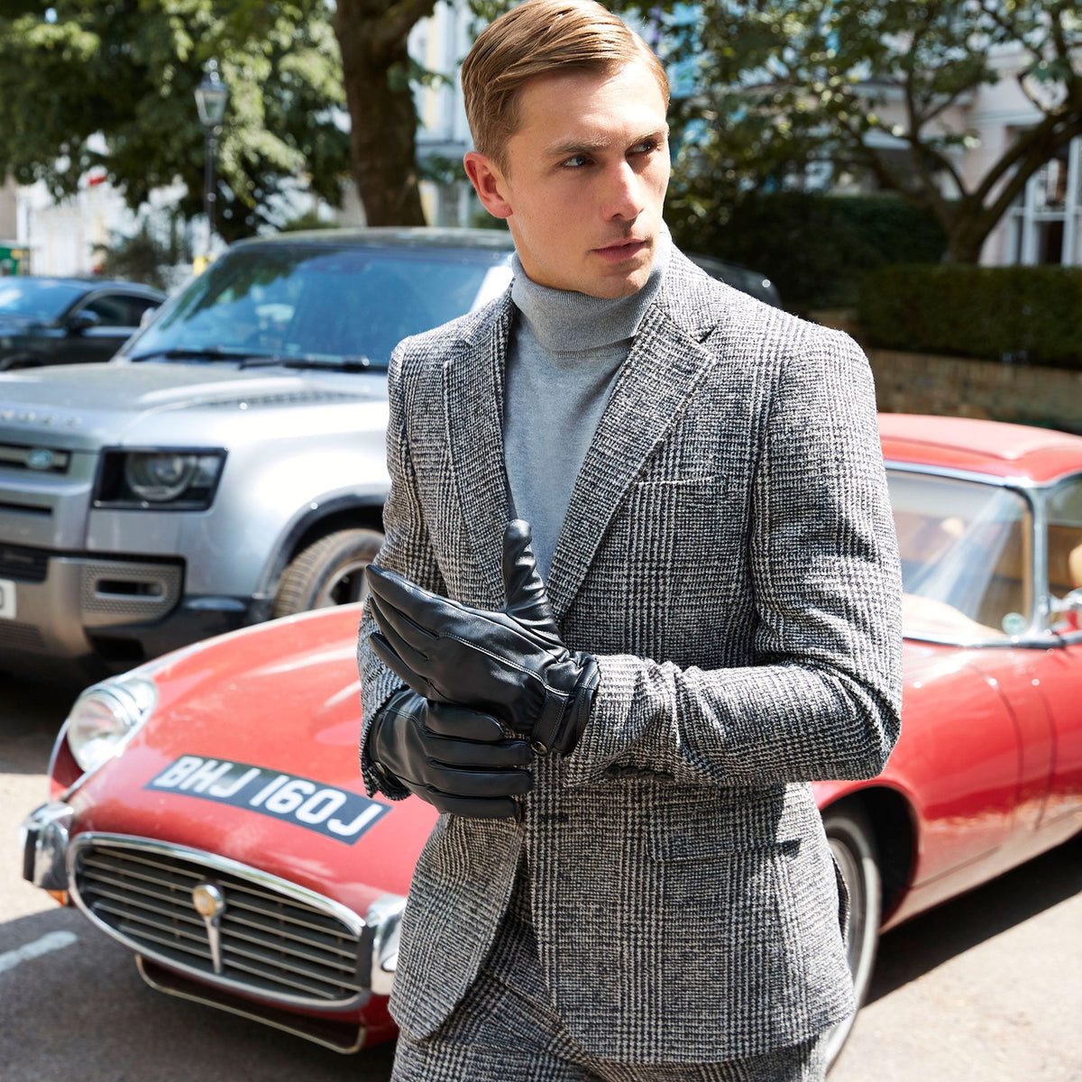 Man wearing touchscreen leather gloves with silver cashmere scarf and tweed jacket walking around the city