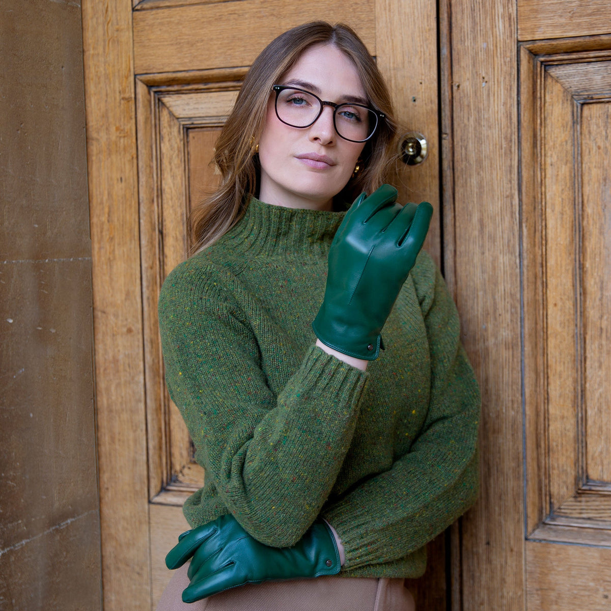 A woman wearing touchscreen single point faux fur lined leather gloves in forest by a door