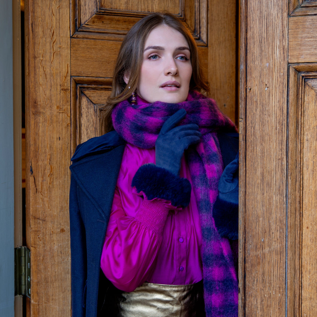 Woman wearing Women's touchscreen velour-lined faux suede gloves with faux fur cuffs in navy by a grand door