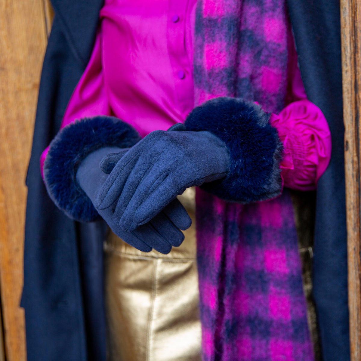 Woman wearing Women's touchscreen velour-lined faux suede gloves with faux fur cuffs in navy by a grand door