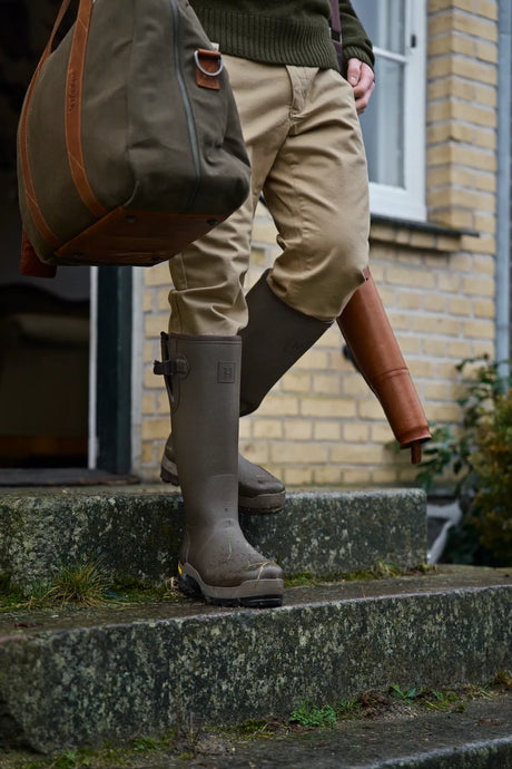Man wearing Härkila Forester wellington boots outside a country house