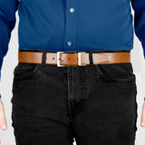 Man wearing heritage reversible full-grain leather belt with satin nickel buckle in black/tan, front. 