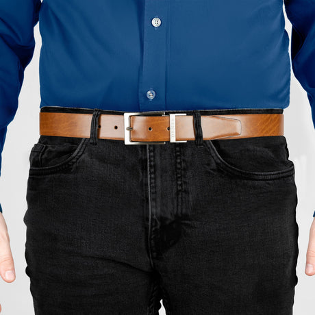 Man wearing heritage reversible full-grain leather belt with satin nickel buckle in black/tan, front. 