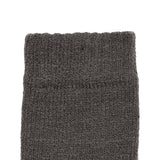 Women's cable knit gloves in dark grey, left hand close up. 