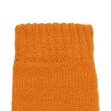 Women's cable knit gloves in orange, left hand close up. 
