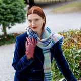 Woman wearing touchscreen single point faux fur lined leather gloves in wine red, in a  blue coat and scarf outside. 