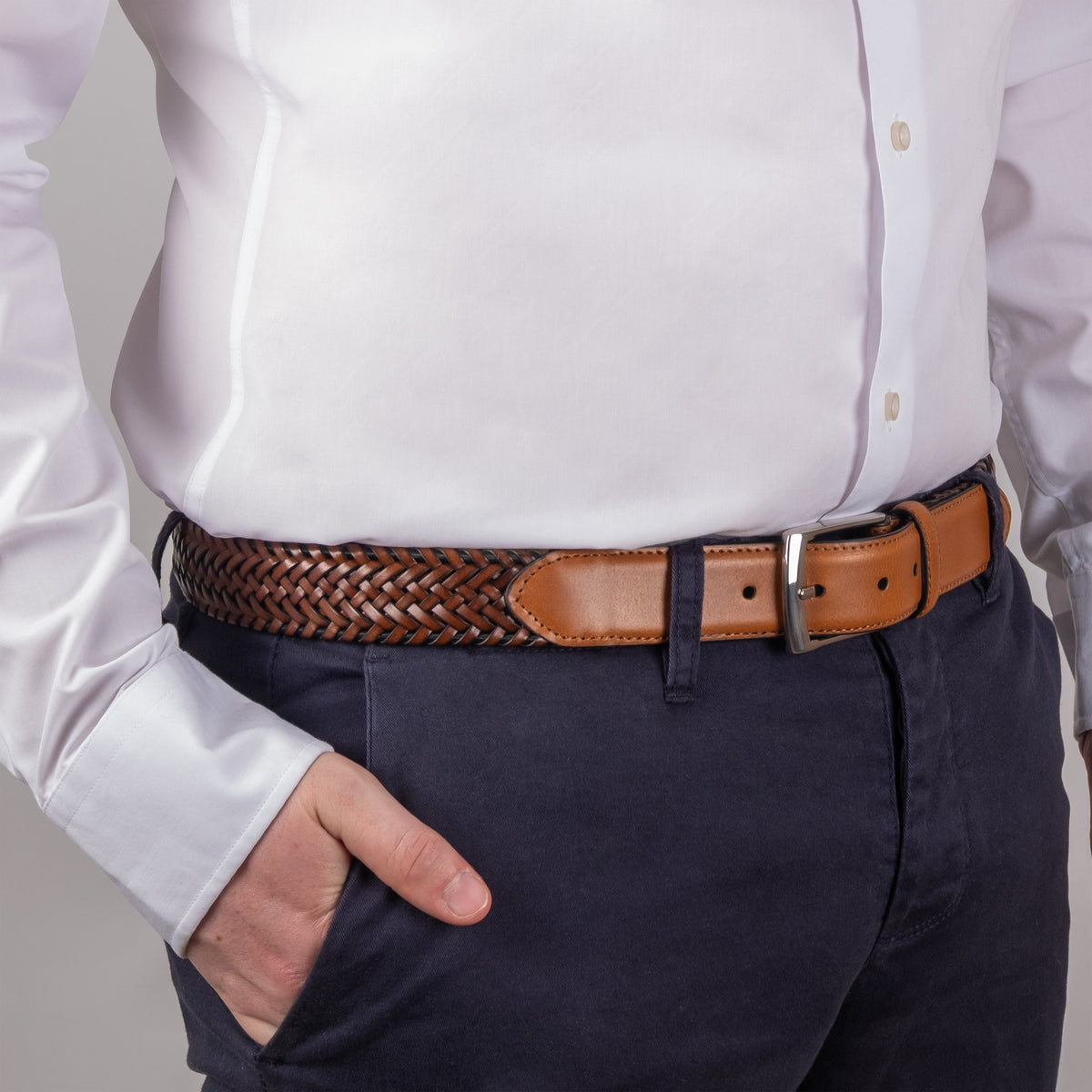 Man wearing woven leather belt with satin nickel buckle in tan, side on close up, hand in pocket