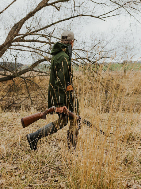 Swazi Wapiti XP Hunting Jacket in Olive, rear view while carrying outdoor equipment