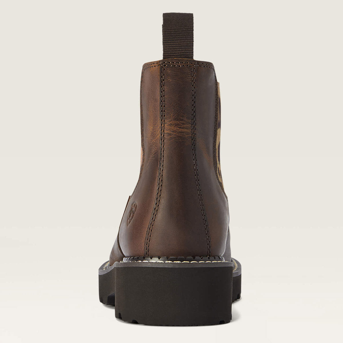 Brown leather boot with a black sole on a beige background
