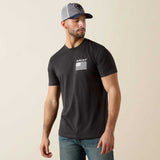 Man wearing a black t-shirt with Ariat logo and gray cap on beige background
