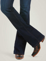 Dark blue jeans worn with brown cowboy boots on a light gray background