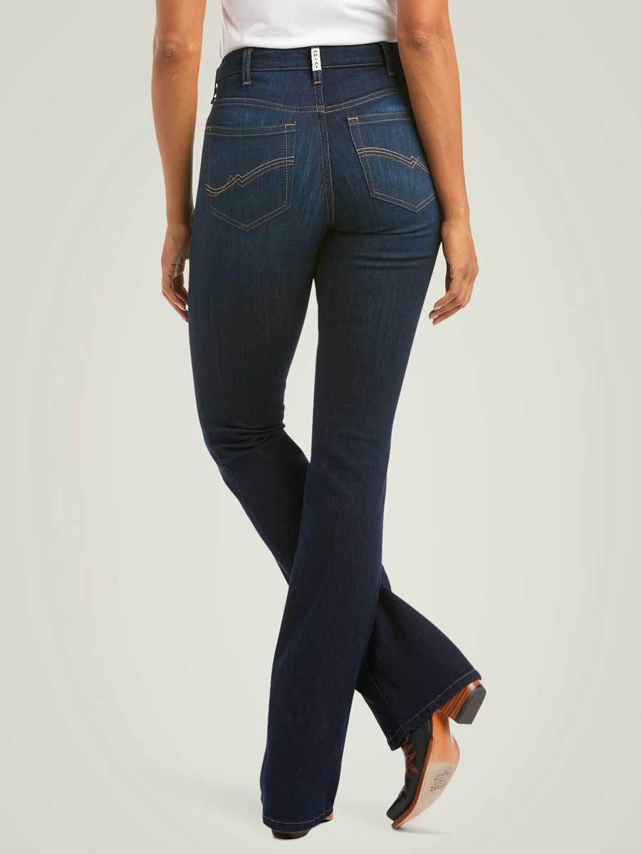 Person wearing dark blue flared jeans on a light gray background