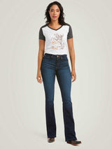 Woman wearing a graphic t-shirt and dark blue jeans on a plain background