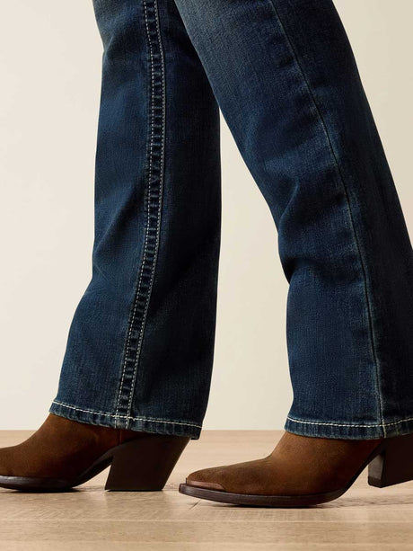 Person wearing blue jeans and brown cowboy boots on a neutral background