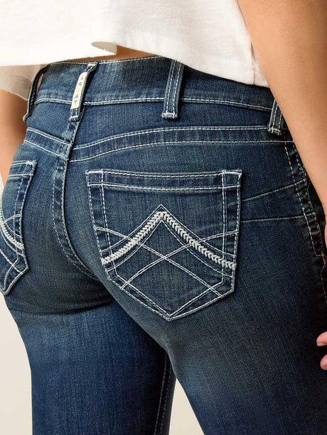 Close-up of blue jeans with a decorative pocket on a neutral background