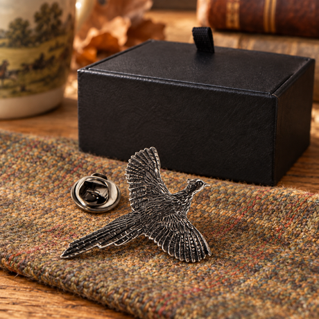 Farley's flying pheasant pewter lapel pin badge on country tweed beside the black presentation box