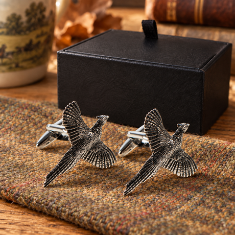 Farley's flying pheasant English pewter cufflinks on tweed beside the black presentation box