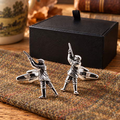 Farley's rhodium-plated gamekeeper shooting cufflinks on tweed beside the black presentation box