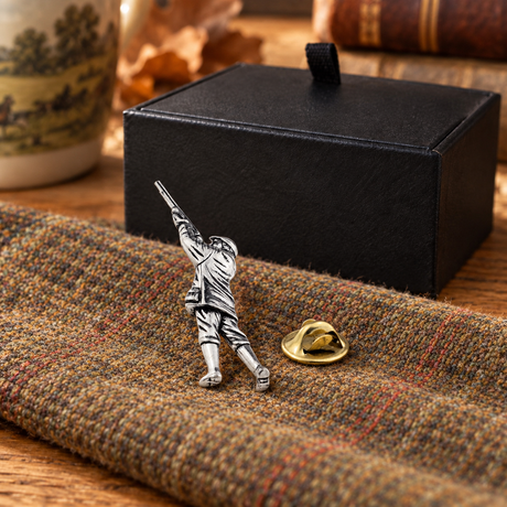 Farley's English pewter gamekeeper lapel pin badge with its clasp on tweed beside the black presentation box