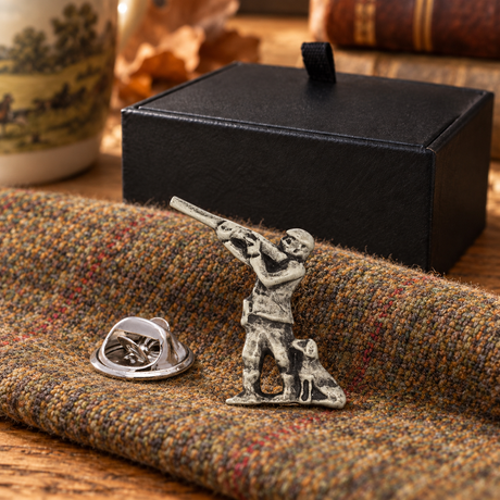 Farley's hunter and dog English pewter lapel pin badge on tweed beside the black presentation box