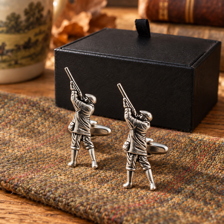 Farley's huntsman gamekeeper English pewter cufflinks displayed on tweed beside the black presentation box