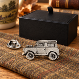 Farley's Land Rover Defender pewter lapel pin badge on tweed beside the black presentation box