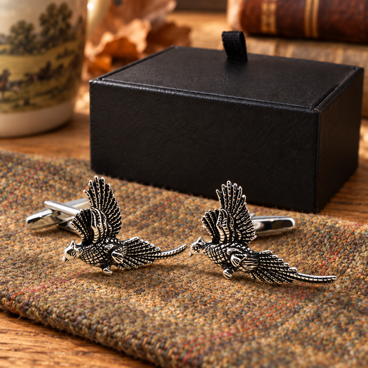 Farley's rhodium-plated pheasants in flight cufflinks displayed on tweed beside the black presentation box
