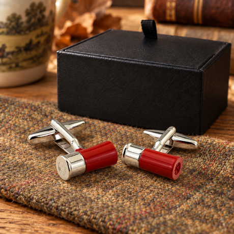 Red and silver-tone shotgun cartridge cufflinks on country tweed beside Farley's black presentation box