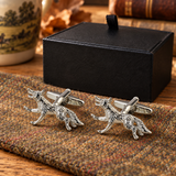 Pair of Farley's running fox English pewter cufflinks on tweed beside the black presentation box