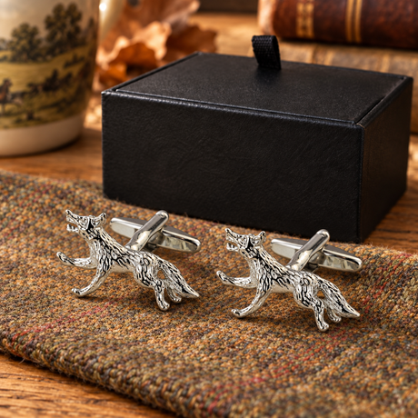 Pair of Farley's running fox English pewter cufflinks on tweed beside the black presentation box