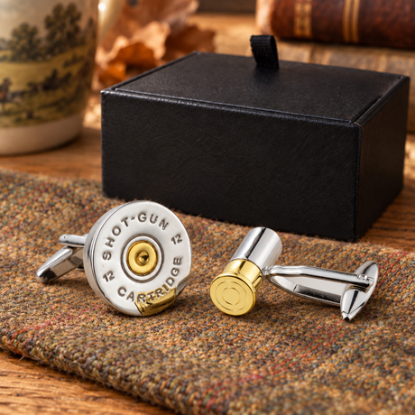 Farley's rhodium plated shotgun cartridge and end cap cufflinks on tweed beside the black presentation box