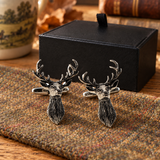 Pair of Farley's stag head English pewter cufflinks on tweed beside the black presentation box