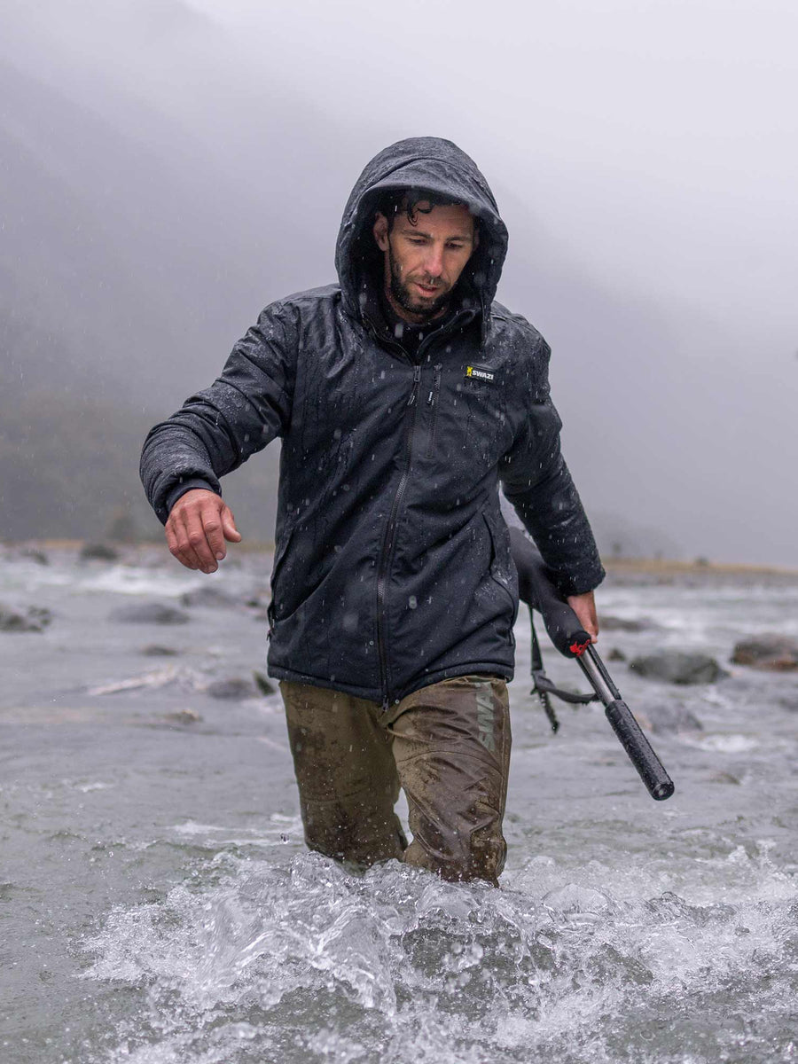 Swazi Geyser Jacket in Black, worn while wading through a river