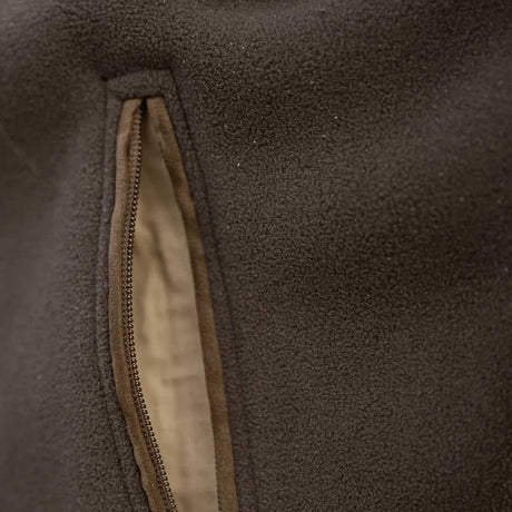 Close-up detail of a dark brown fleece jacket showing a vertical zippered pocket with a tan zipper trim and a light beige interior lining.