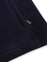 Close-up of a navy blue garment with a gold button on a white background