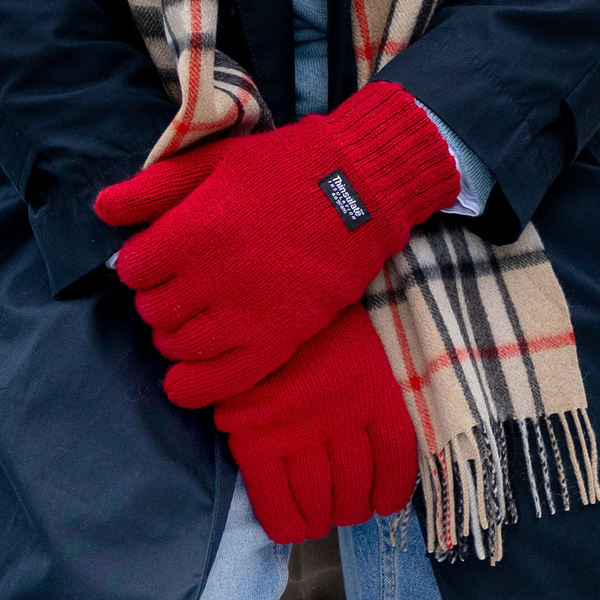 Close up of men's wearing thinsulate knitted gloves in berry with a coat outdoors