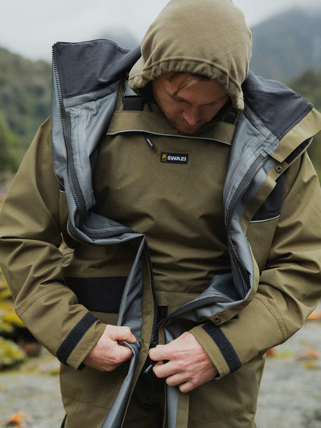 Swazi Torrent Waterproof Jacket in Ranger / Black, worn while crouching in woodland
