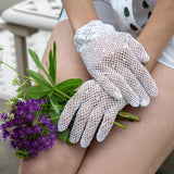 Close up of women's hands wearing cotton crochet gloves in ecru holding flowers