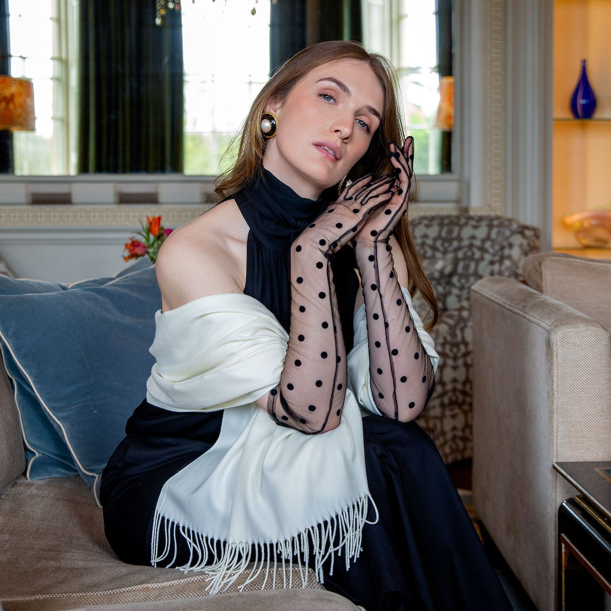 Woman wearing plain pashmina shawl with tassels ivory, over her shoulders. 