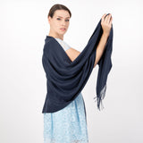 Woman wearing plain pashmina shawl in navy - holding one side up