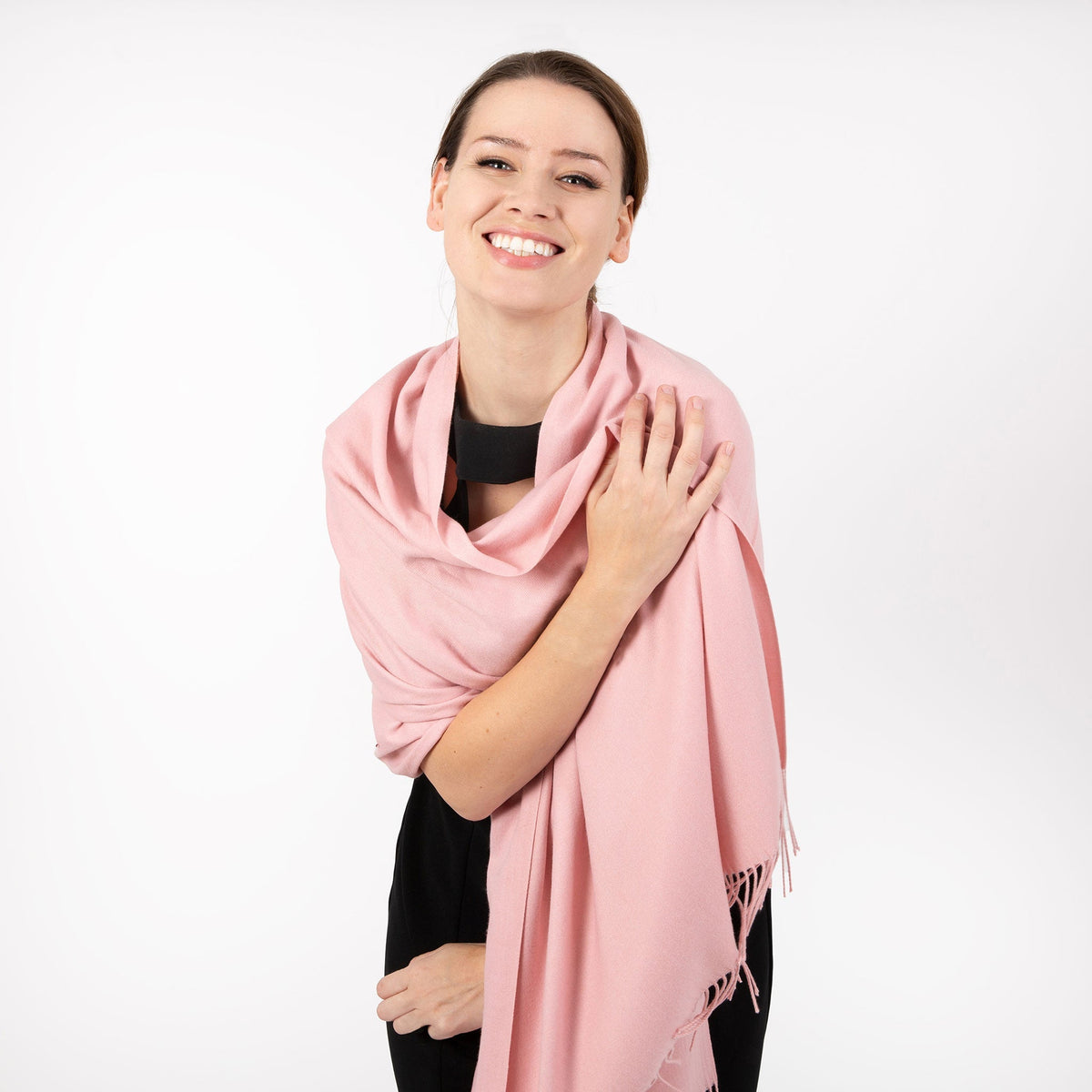 Woman wearing plain pashmina in pale pink, in a loop over shoulders. 