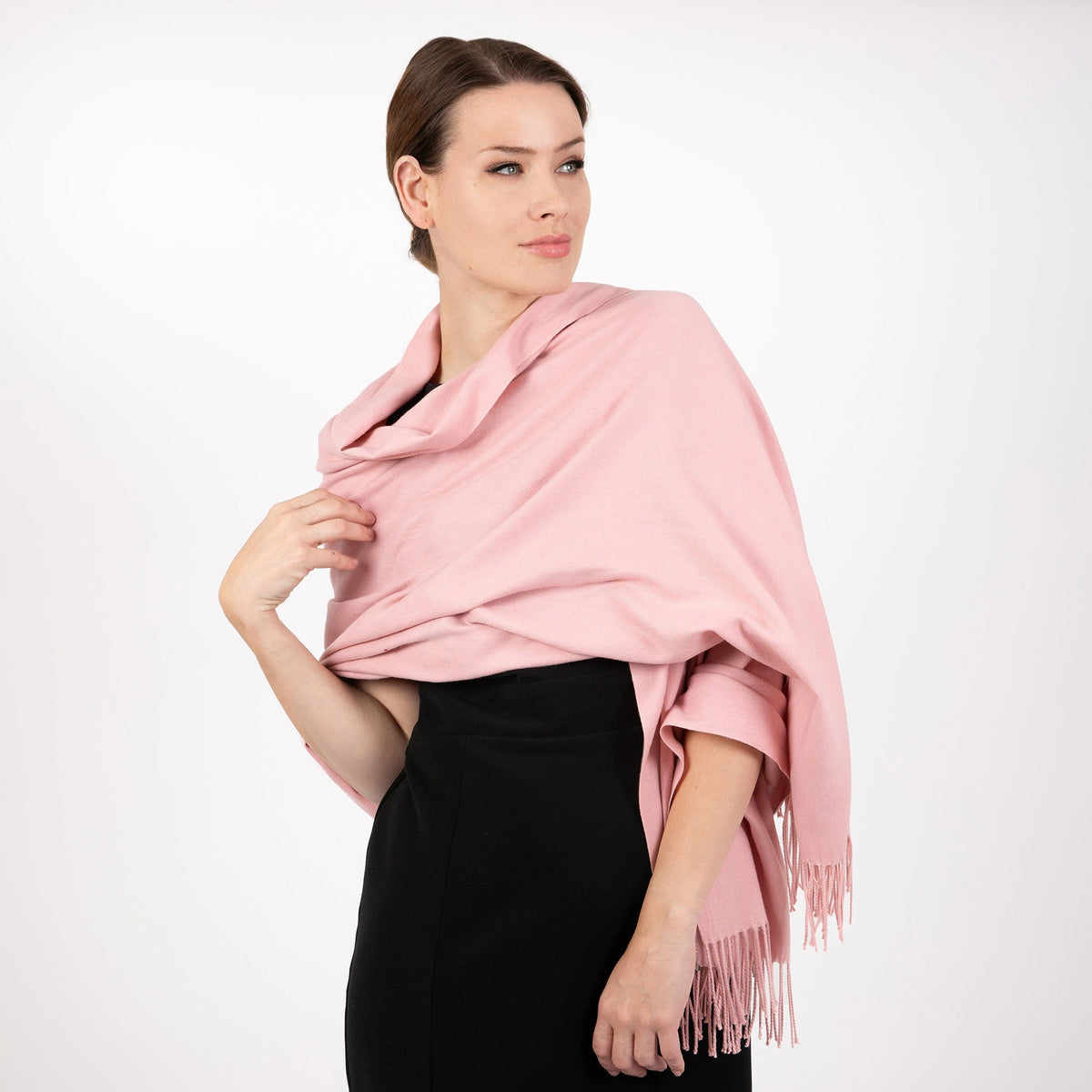 Woman wearing plain pashmina in pale pink in studio. 