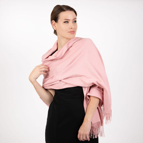 Woman wearing plain pashmina in pale pink in studio. 
