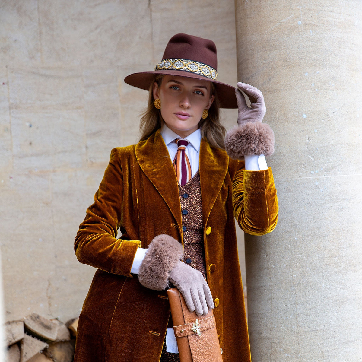 Woman wearing touchscreen velour-lined faux suede gloves with faux fur cuffs in camel at a park