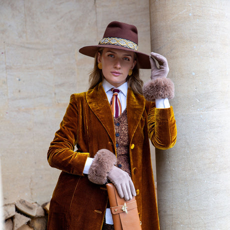 Woman wearing touchscreen velour-lined faux suede gloves with faux fur cuffs in camel at a park